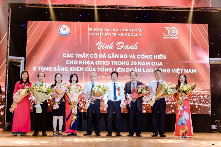 May be an image of 9 people, people standing and text that says '回 TRƯỜNG ĐẠI HỌC CÔNG ĐOÀN KHOA QUẦN TRI KINH DOANH Vinh Danh CÁC THẨY CÔ ĐÃ GẮN Bä VÀ CỐNG HIẾN CHO KHOA QTKD TRONG 30 NĂM QUA TẶNG BẰNG KHEN CỦA Tá»NG LIÊN ĐOÀN LAO ÔNG VIỆT NAM láng Ona'